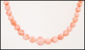 A vintage pink salmon coral bead necklace having a floral gilt clasp.