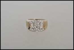 A stamped 9k gold ring having a crossed c's design set with white accent stones. Weight 6.4g. Size