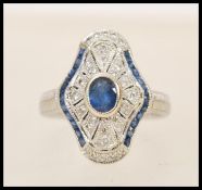 A 1920's 18ct white gold art deco panel ring set with a central oval cut sapphire in a shaped