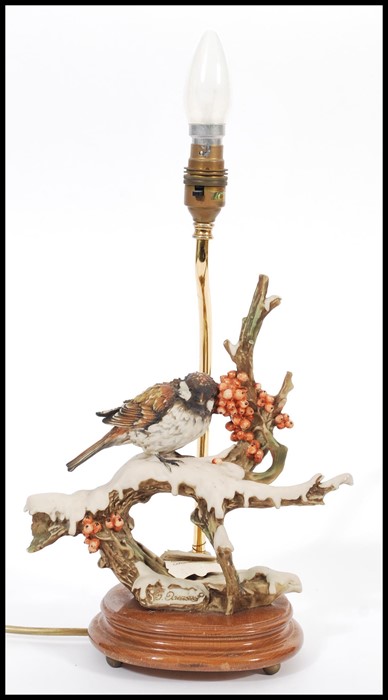 A vintage Capodimonte ceramic table lamp in the form of a bird raised on naturalistic scenery and