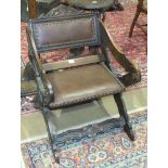 An Edwardian stained wood low X-frame chair with padded back and seat.