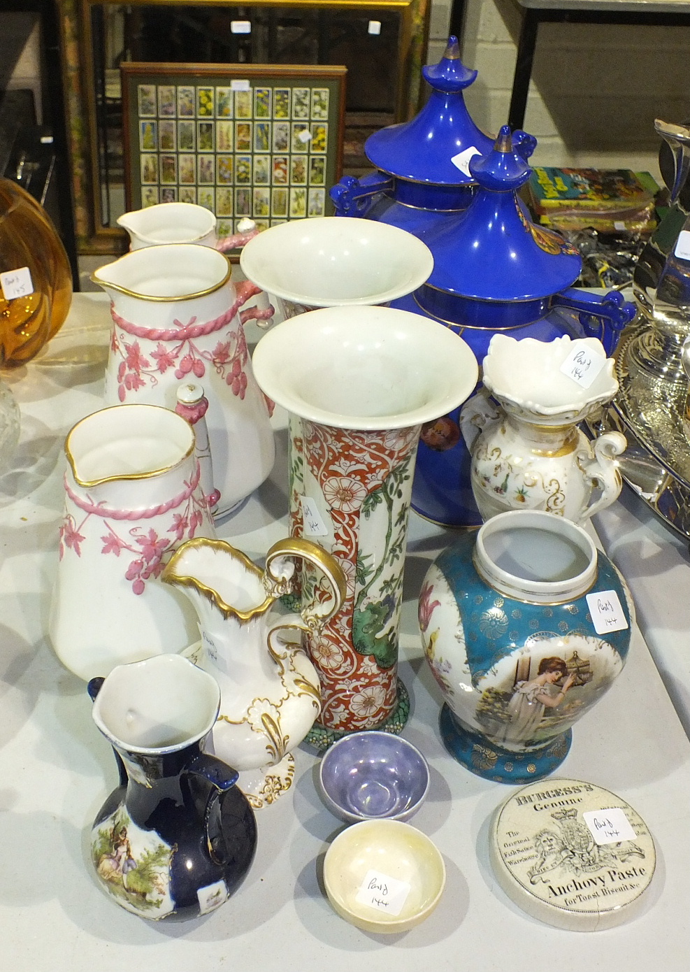 A pair of Falconware two-handled lidded vases decorated with Oriental figures and lanterns on a blue