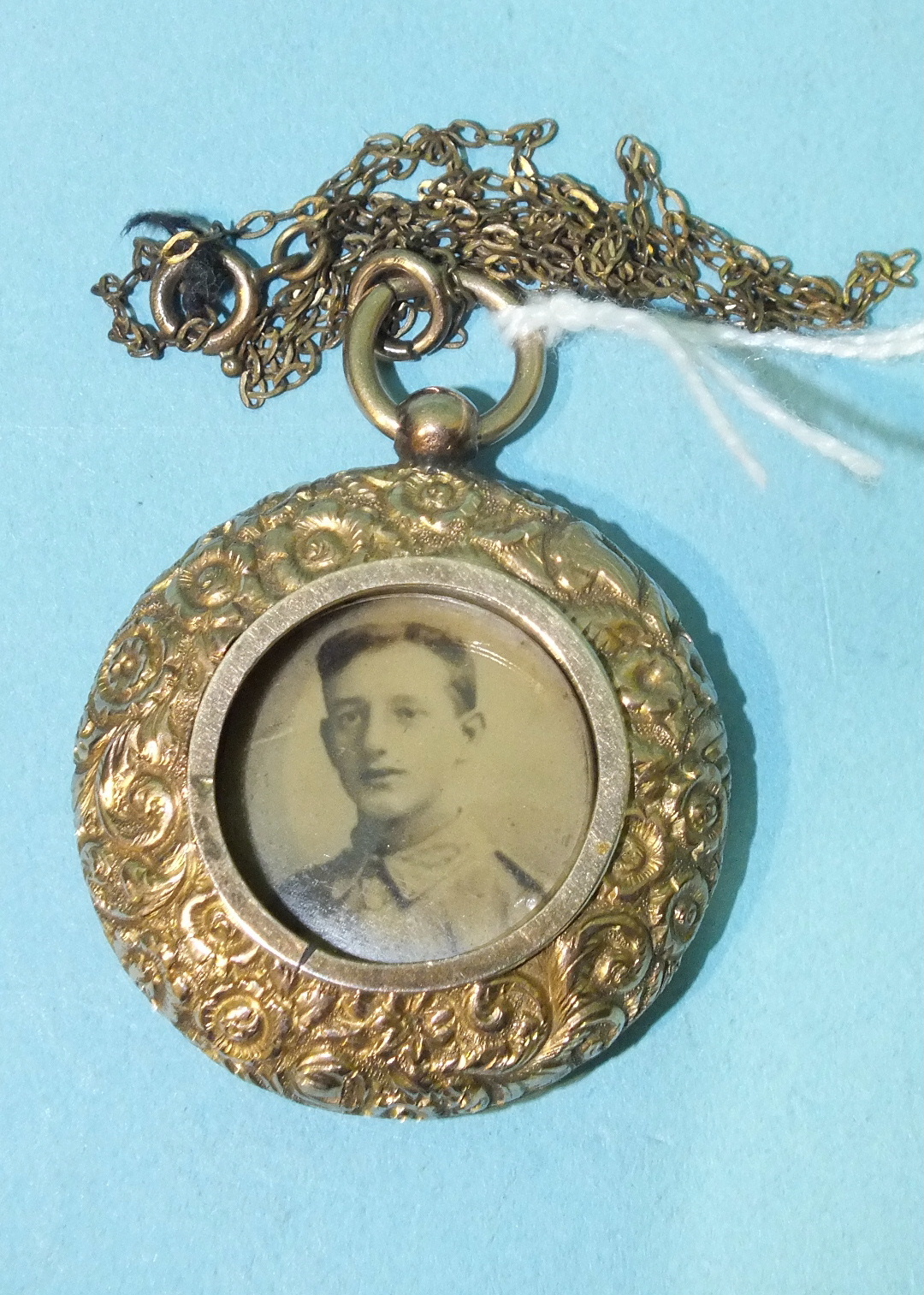 A 19th century circular gold locket with raised floral decoration, on plated chain.