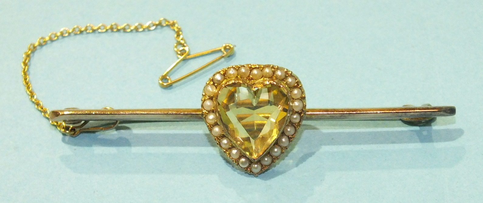 An Edwardian 9ct gold bar brooch set a heart-shaped citrine within a surround of seed pearls, 6cm