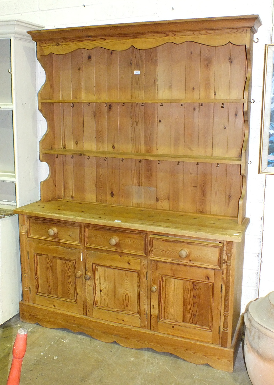 A modern pine dresser, the open shelved upper section above three drawers and three cupboard