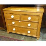 A stained pine low chest of two short and two long drawers, on turned feet, 97cm wide, 76cm high.