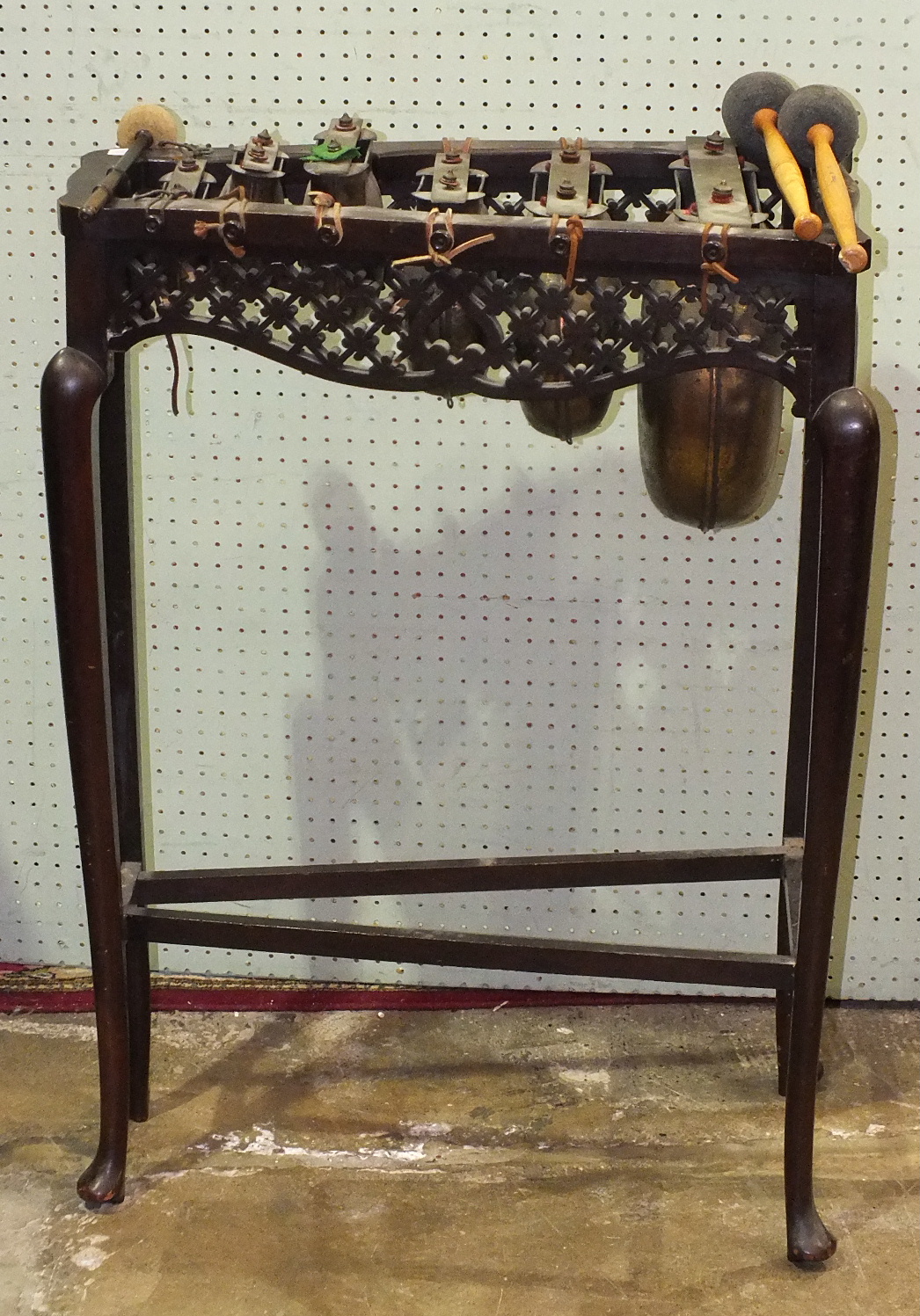 A xylophone of six graduated brass bells, on stained wood stand, 58cm long, 80cm high.