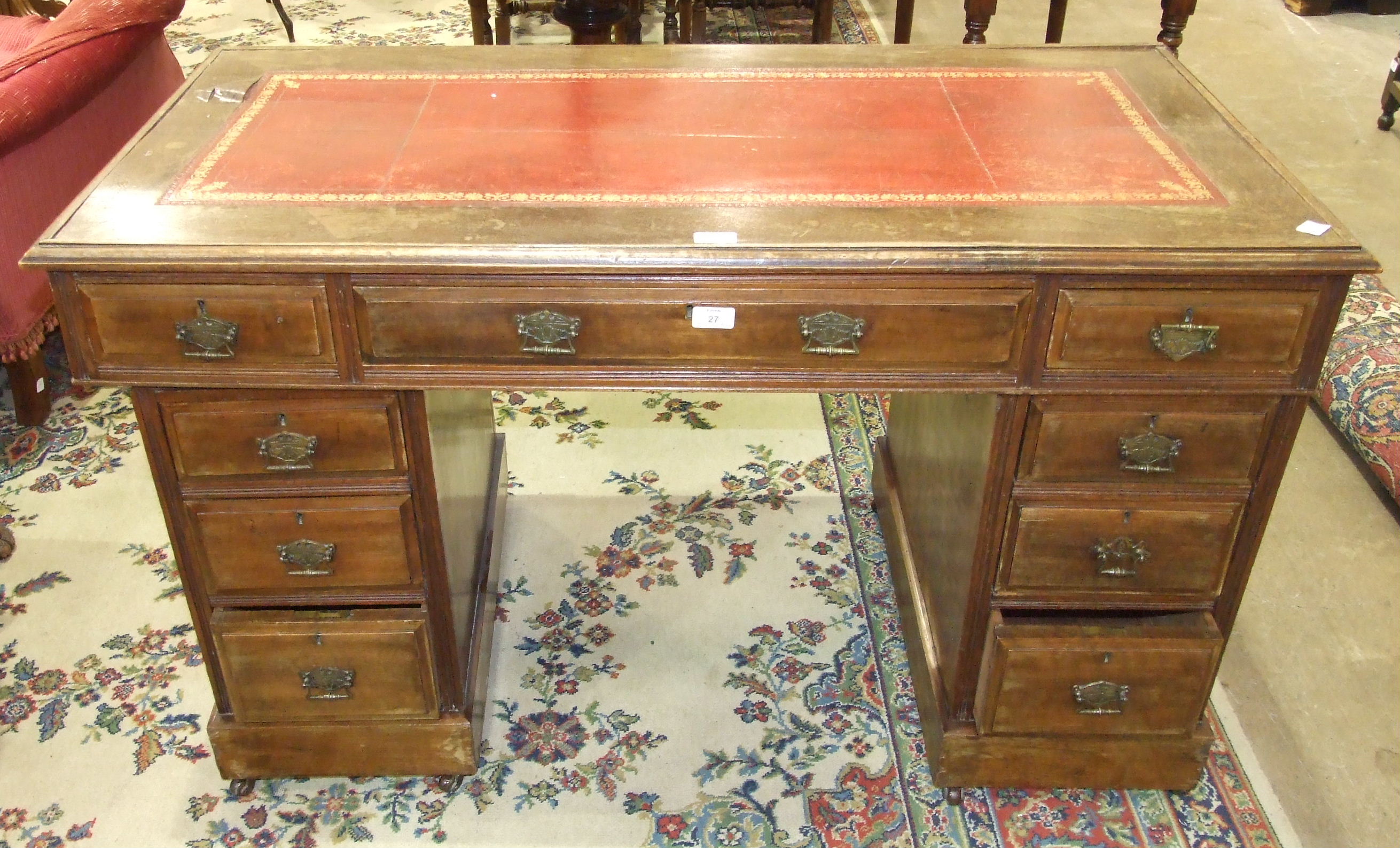 An Edwardian stained wood knee-hole desk, the rectangular top with writing inset above three