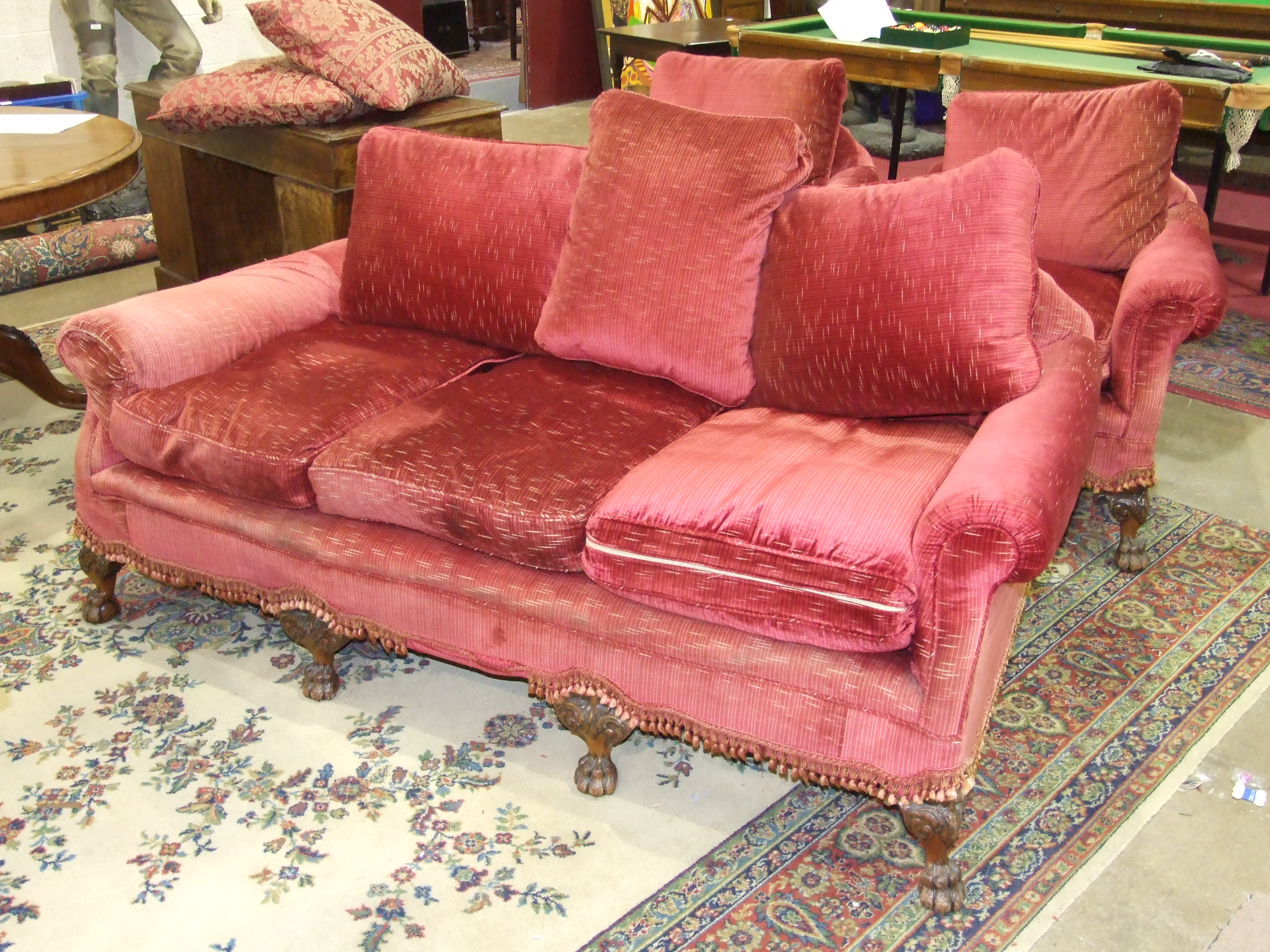 An early 20th century upholstered deep-seated three-seater settee with carved front feet, and a pair