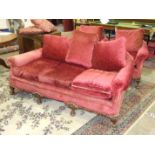 An early 20th century upholstered deep-seated three-seater settee with carved front feet, and a pair