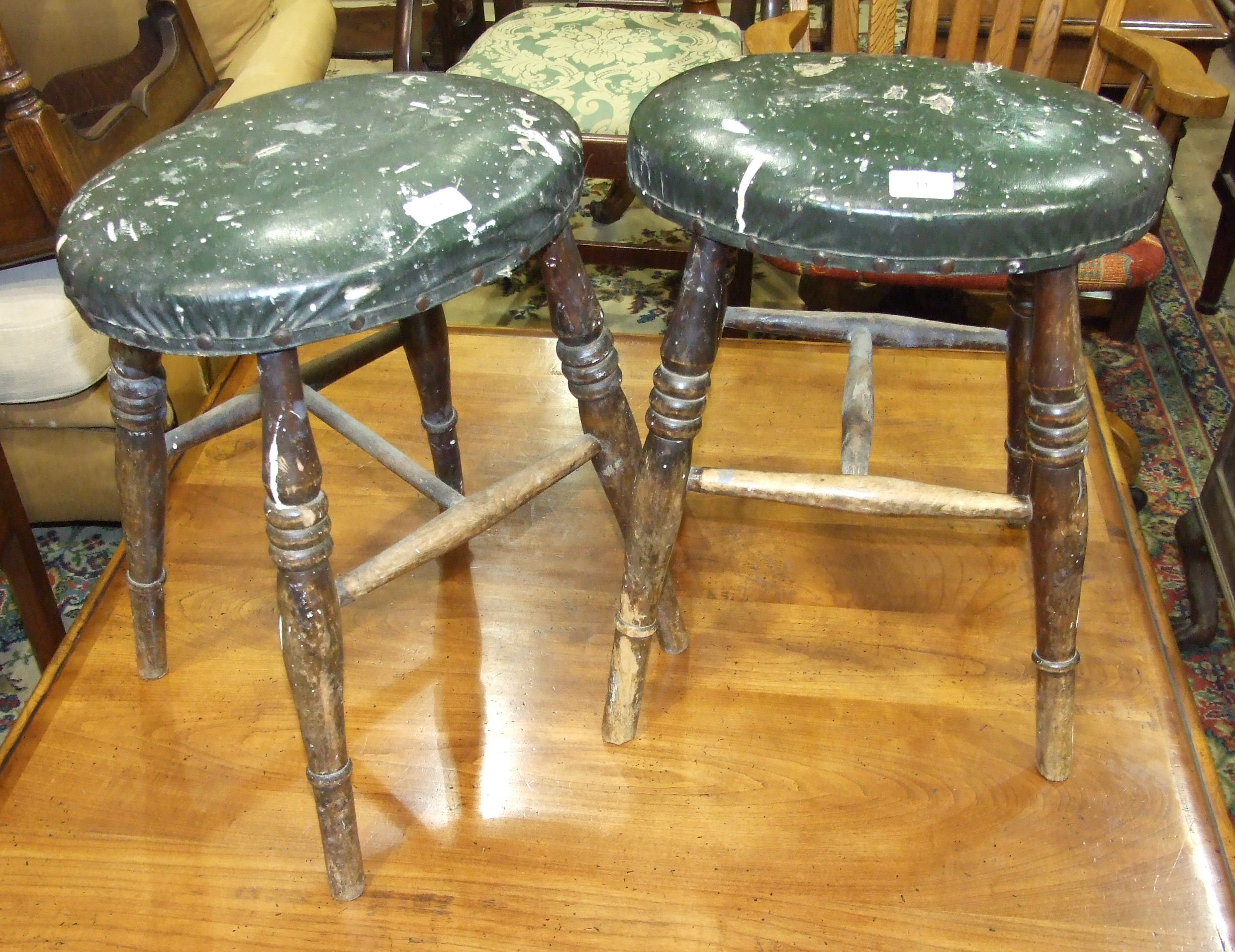 A pair of late 19th/early 20th century stained beech oval seated stools with ring-turned legs,