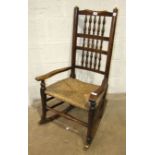 A stained wood rocking chair with spindle back and rush seat.