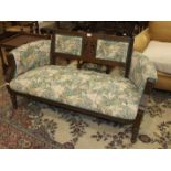 An Edwardian mahogany frame two-seater settee with upholstered back, arms and seat, on turned