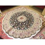 A modern Tabriz circular wool rug with scalloped edge, salmon pink border and foliate design on a