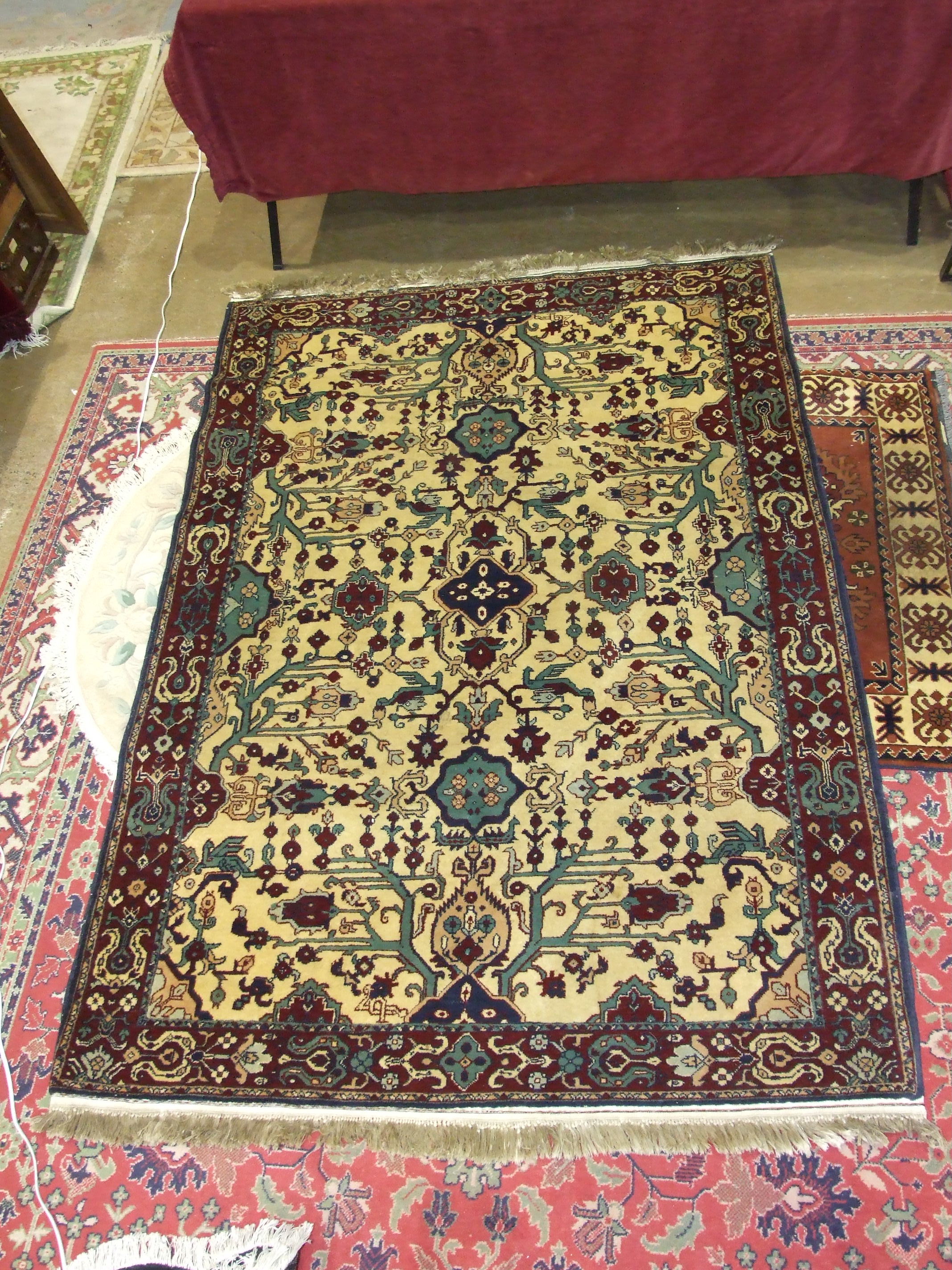 A modern Oriental rug with geometric design on ivory and burgundy field, 220 x 140cm.