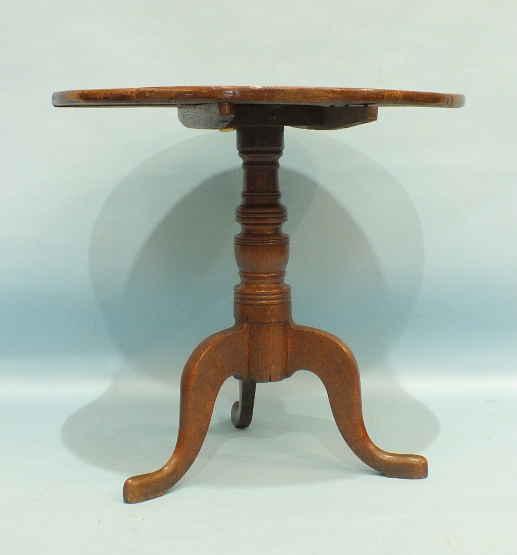 An antique oak tilt-top occasional table on turned column and tripod support, 75cm diameter.