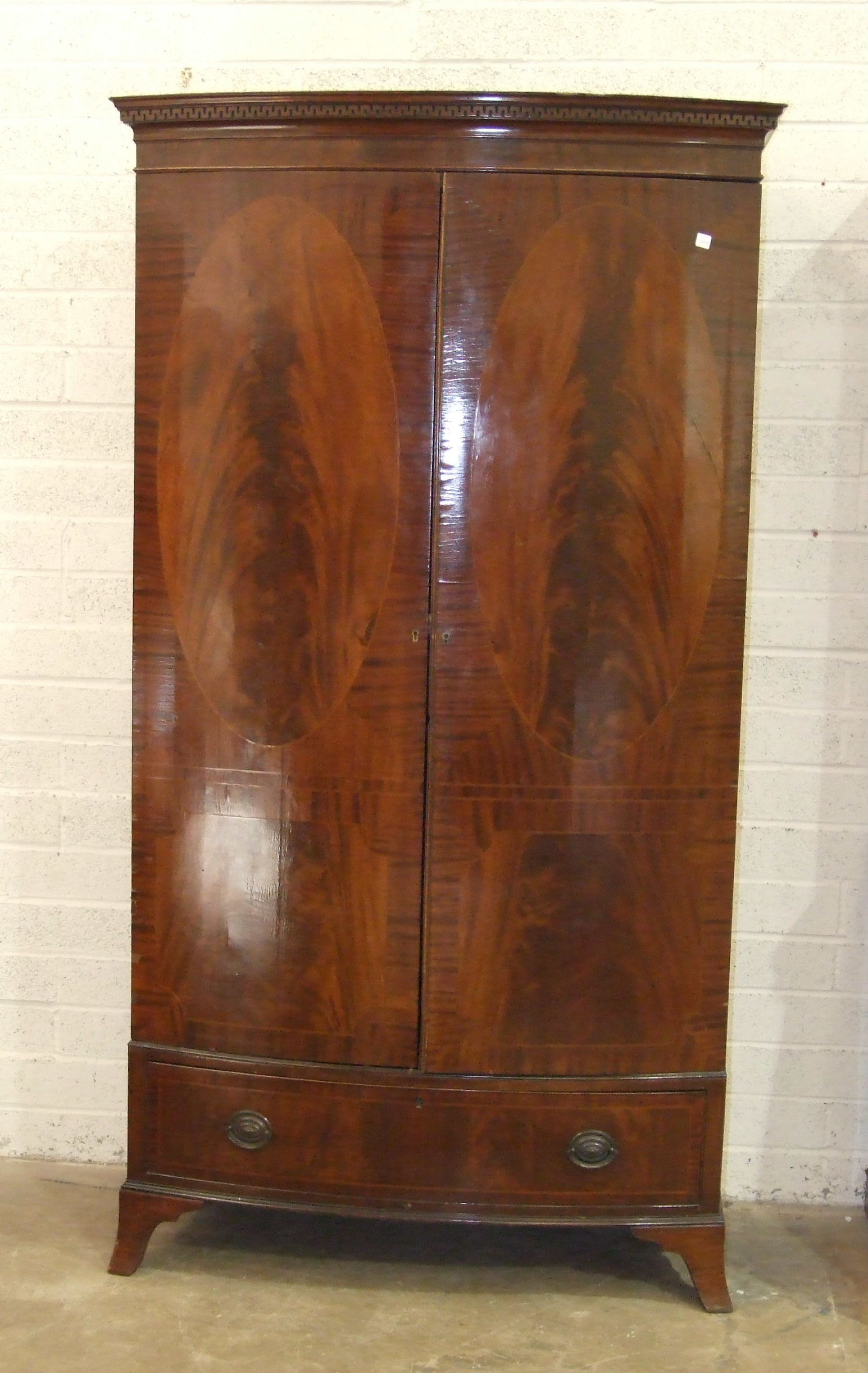 A Georgian-style mahogany bow-fronted two-door wardrobe, with dentil cornice and base drawer,