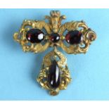 A mid-Victorian brooch of scrolling form set three foil-backed garnet cabochons, with detachable