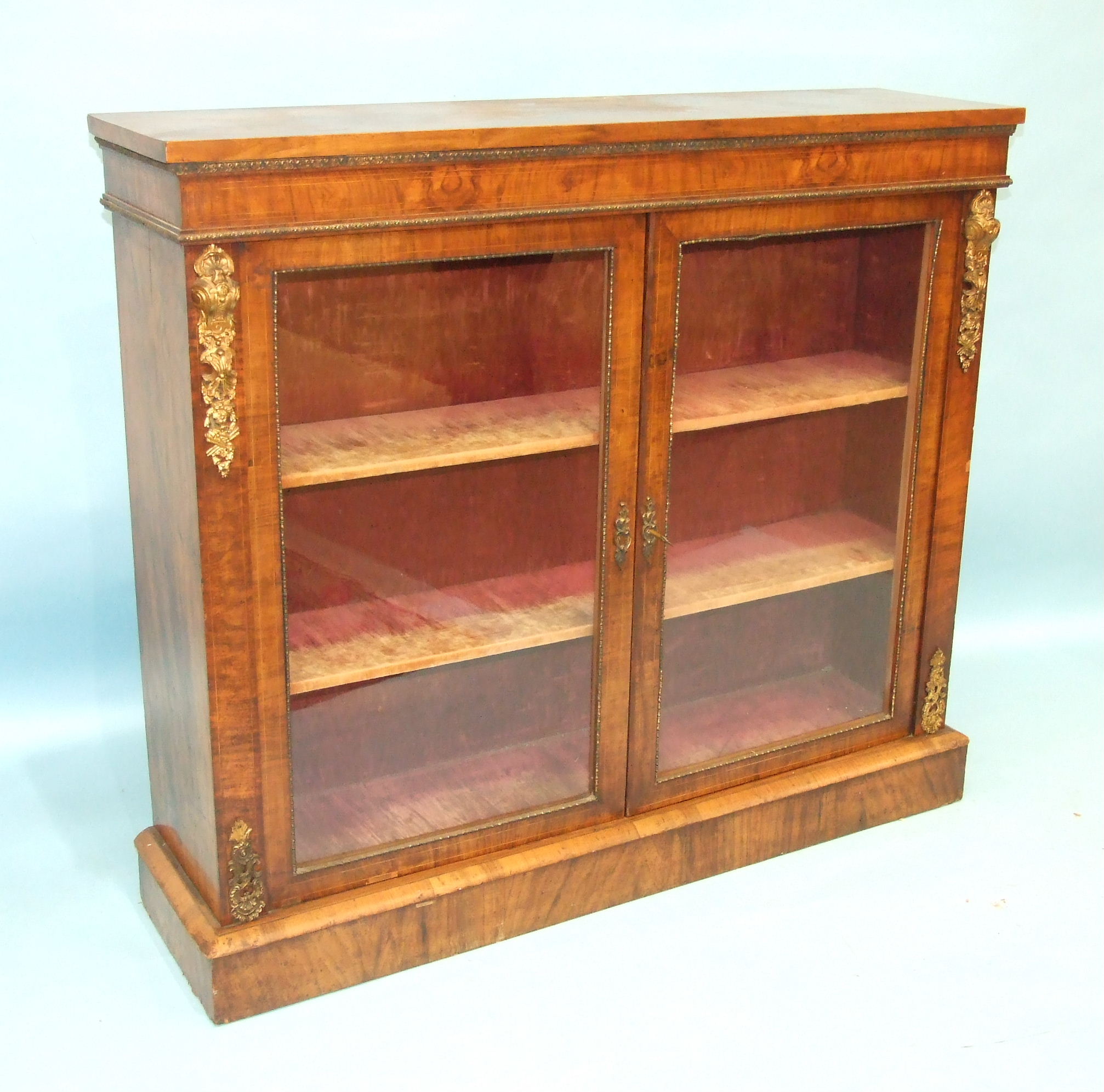A Victorian walnut side cabinet, the rectangular top above a pair of plain glazed doors, on plinth