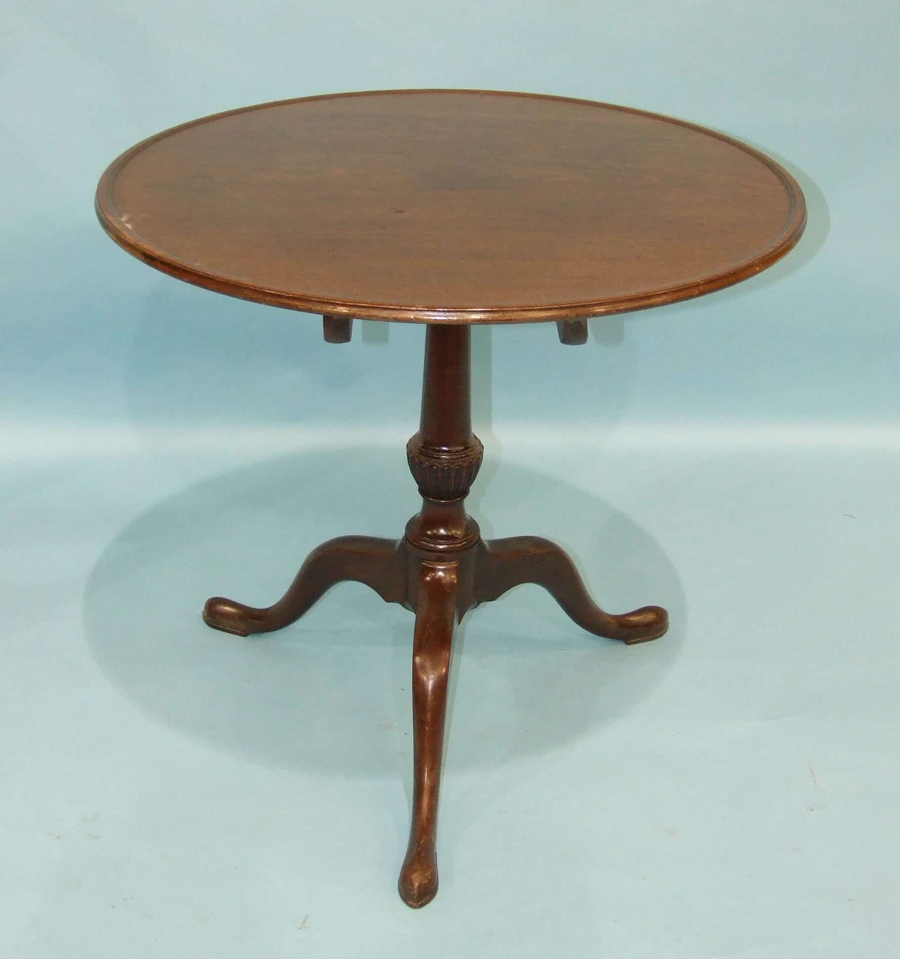 An 18th century mahogany tripod table, the circular top with moulded border, on carved and turned