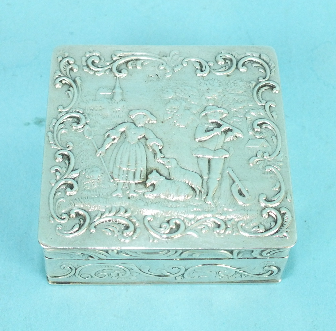 A small Continental silver square box, the lid embossed with a shepherdess and musician within