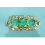 An emerald and diamond cluster ring claw-set an octagonal and two step-cut emeralds within a