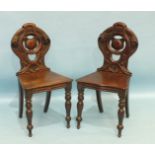 A pair of mahogany hall chairs with pierced backs and shaped solid seats, on turned front legs, (