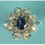 A sapphire and diamond cluster ring claw-set an oval sapphire within two tiers, each of eight