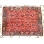 A mid-20th century rug with overall foliate decoration, on a brick red ground, 148 x 210cm.