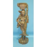 A similar carved wood figure of a semi-naked young woman carrying a piglet, with a basket of fruit