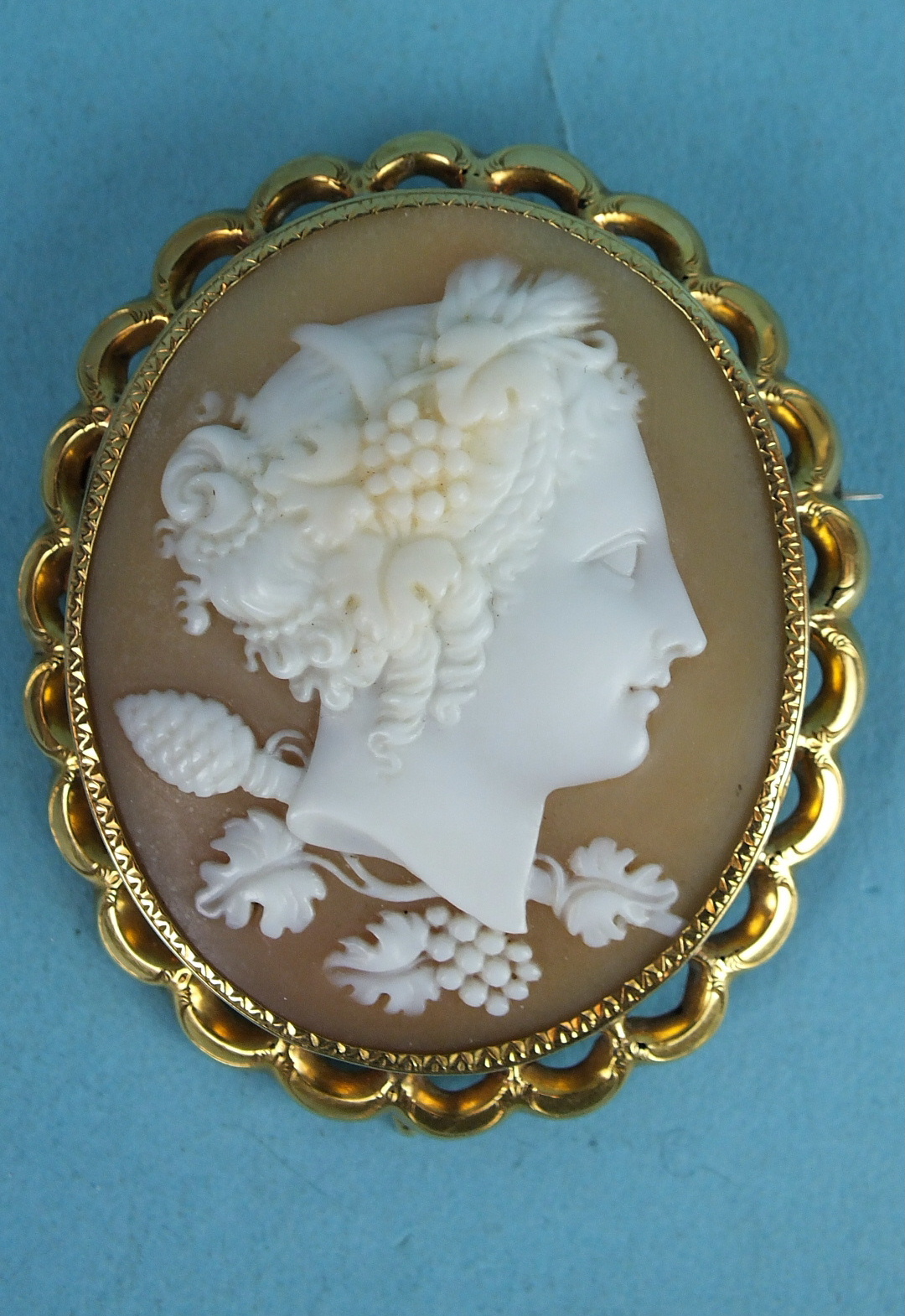 A Victorian shell cameo brooch portraying a bust of Demeter with grapes in her hair and pine cone