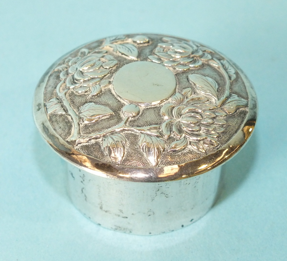 A small Chinese silver pill box of cylinder form, with embossed screw top, maker HC, 4.5cm diameter.