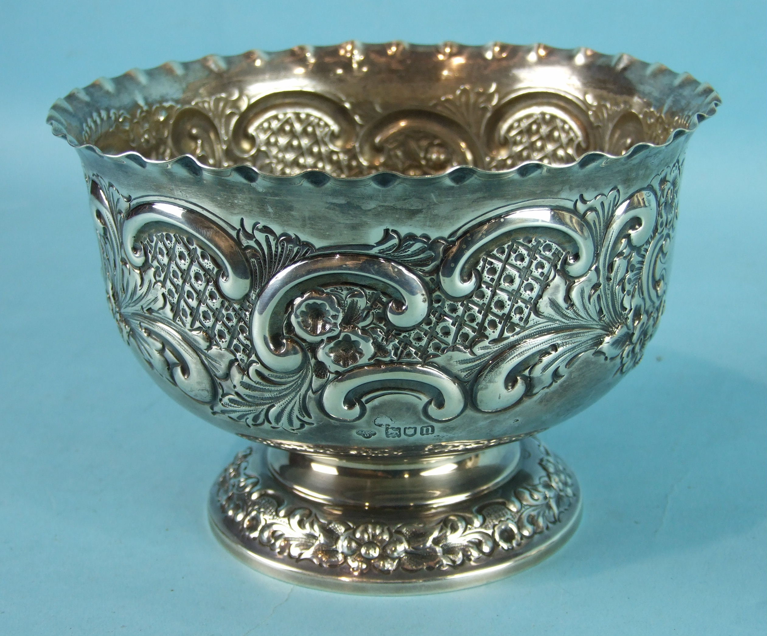 An Edwardian embossed rose bowl with crimped border, on circular foliate foot, by Goldsmiths &