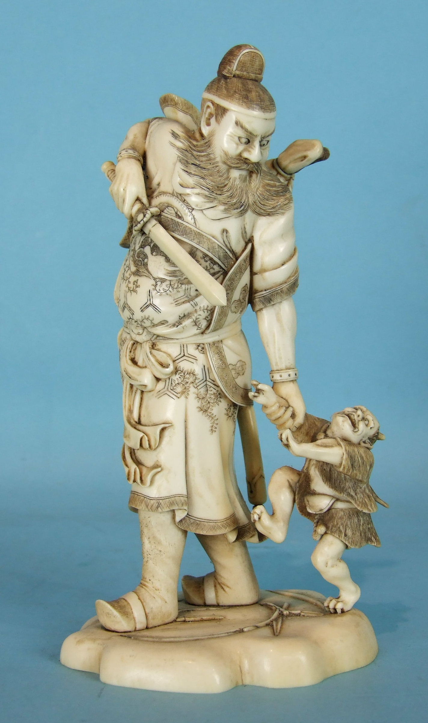 A Japanese ivory okimono of Shoki the demon slayer capturing a young oni, slight damage to