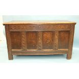 An antique oak coffer with carved panelled front and sides, stiles extended to form feet, 131cm