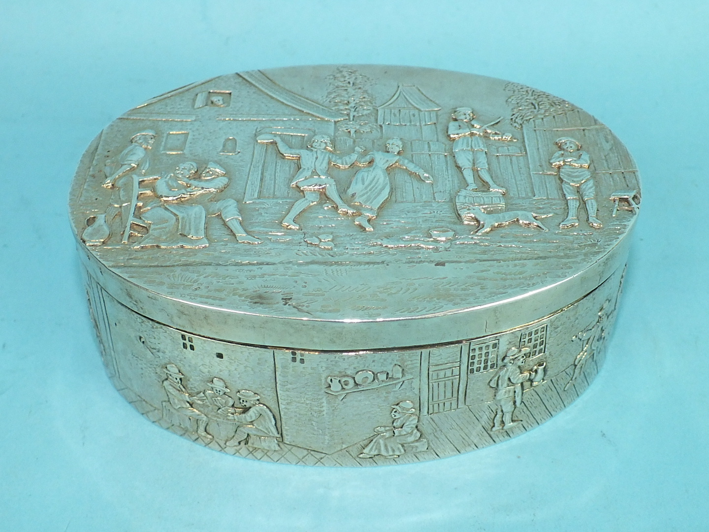 A Continental silver oval hinged trinket box with gilt interior, the lid embossed with country