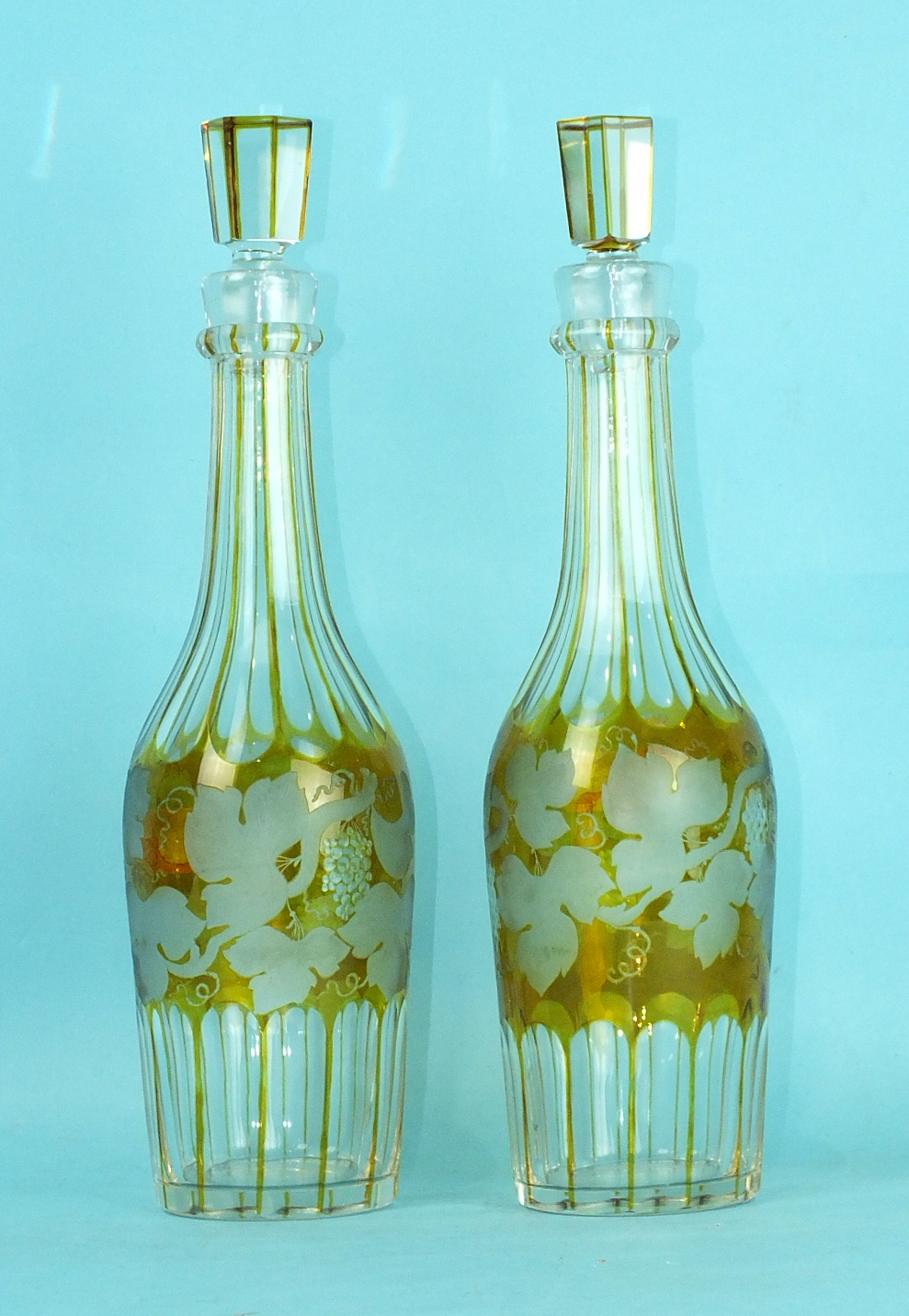 A pair of amber overlay cut-glass faceted decanters and stoppers etched with vine leaves and grape