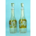 A pair of amber overlay cut-glass faceted decanters and stoppers etched with vine leaves and grape