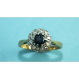A sapphire and diamond cluster ring claw-set a round-cut sapphire within a surround of ten 8/8-cut