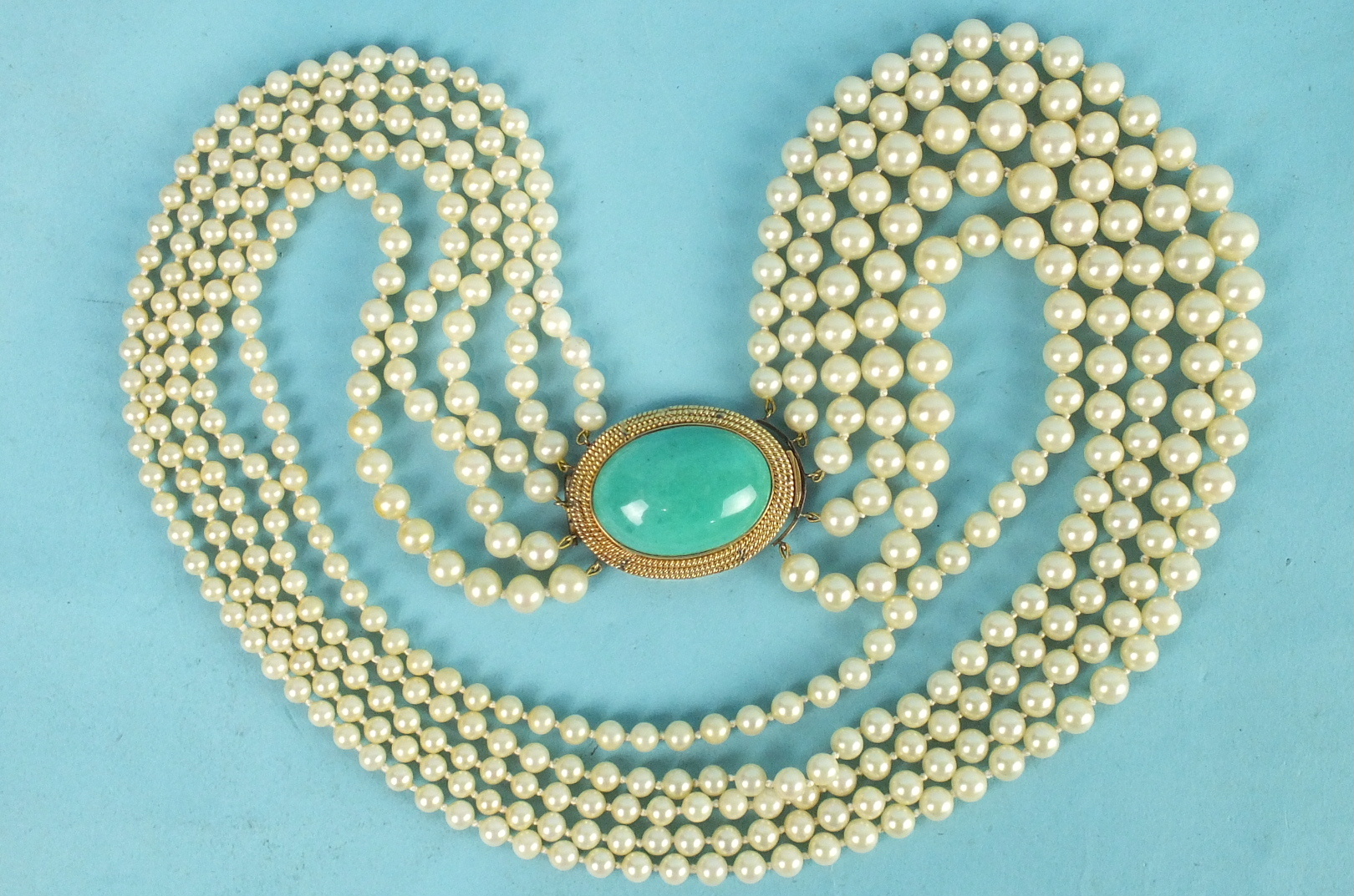 A necklace of five strands of simulated pearls to a large turquoise cabochon-set box clasp with