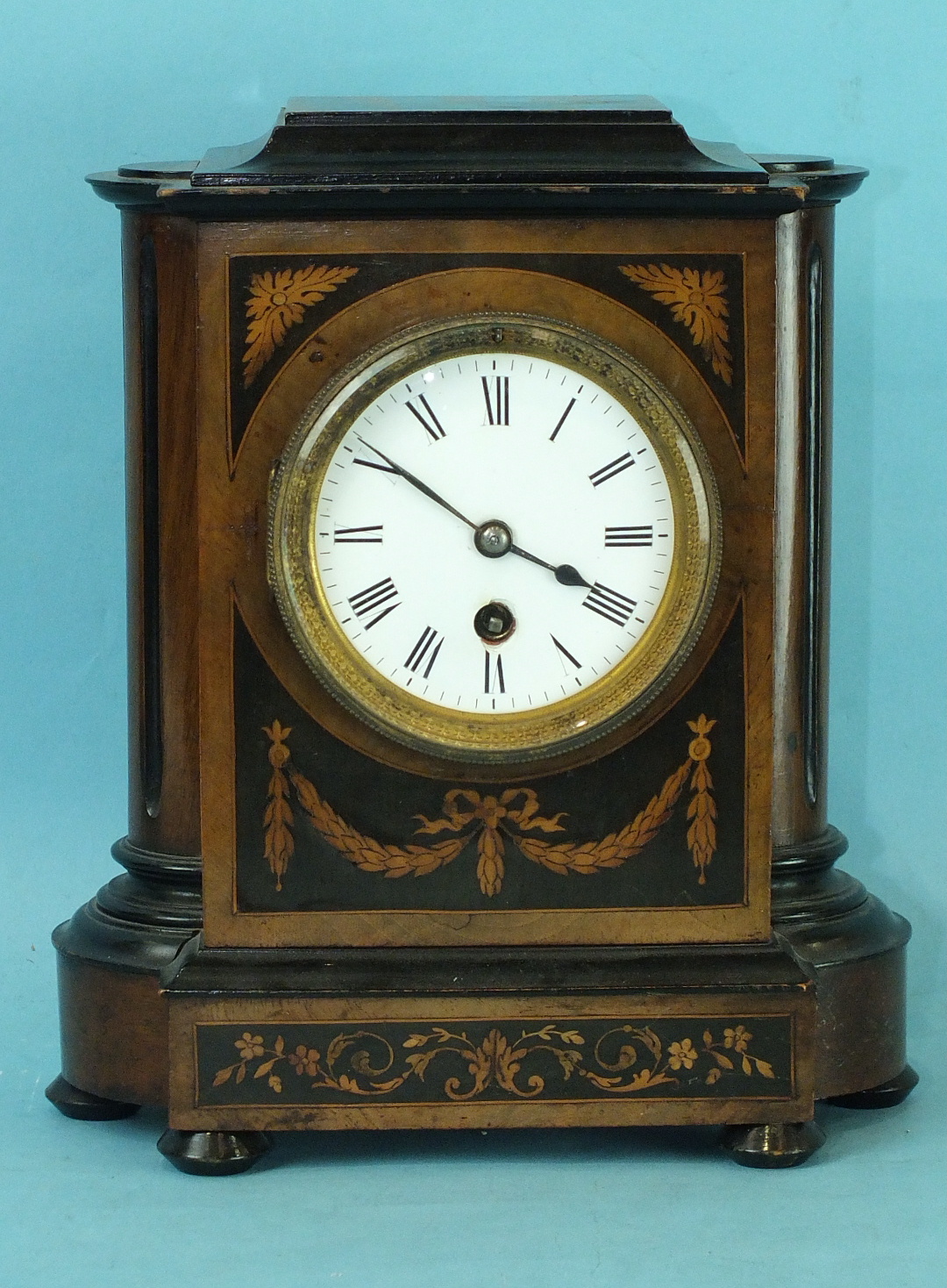 A 19th century walnut and mahogany mantel clock with circular enamelled dial and drum movement, 27cm