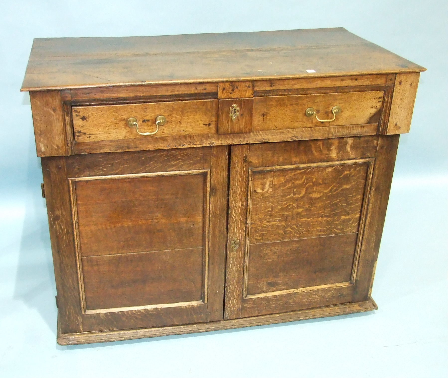 An antique oak chest having a frieze drawer above a pair of panelled doors, enclosing three