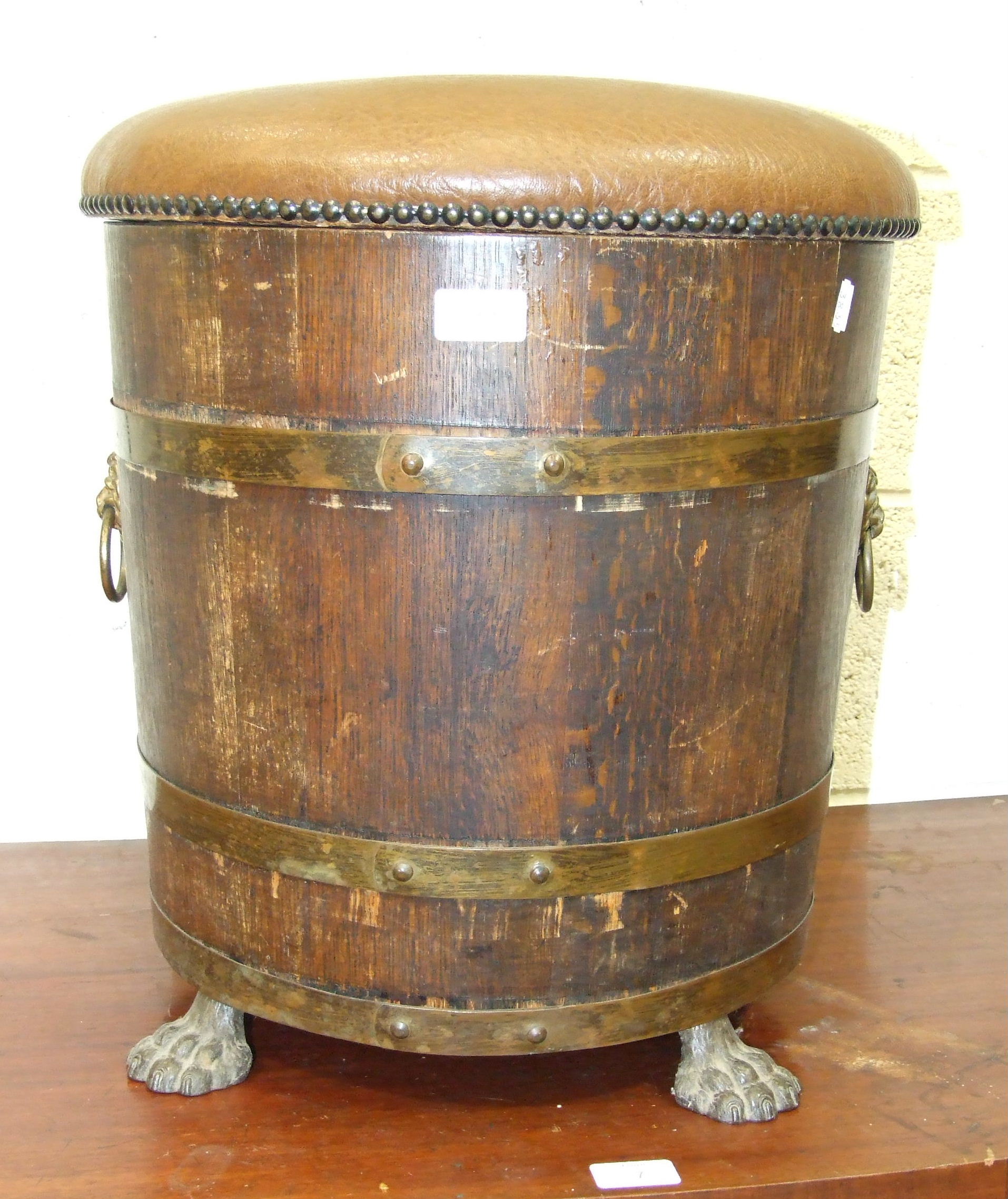 An oak and brass coopered log bin/stool, with metal liner, padded seat and lion mask ring handles,