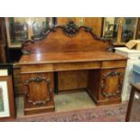 A Victorian mahogany pedestal sideboard, the carved back above three drawers and two cupboard doors,