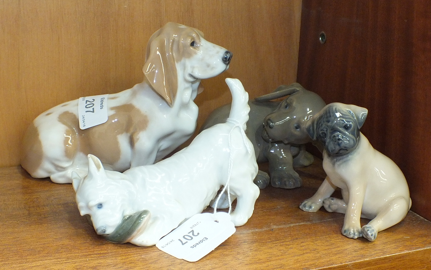 A collection of four Royal Copenhagen dog figures, including 'Dachshund Puppy' No.1407, 'Bassett