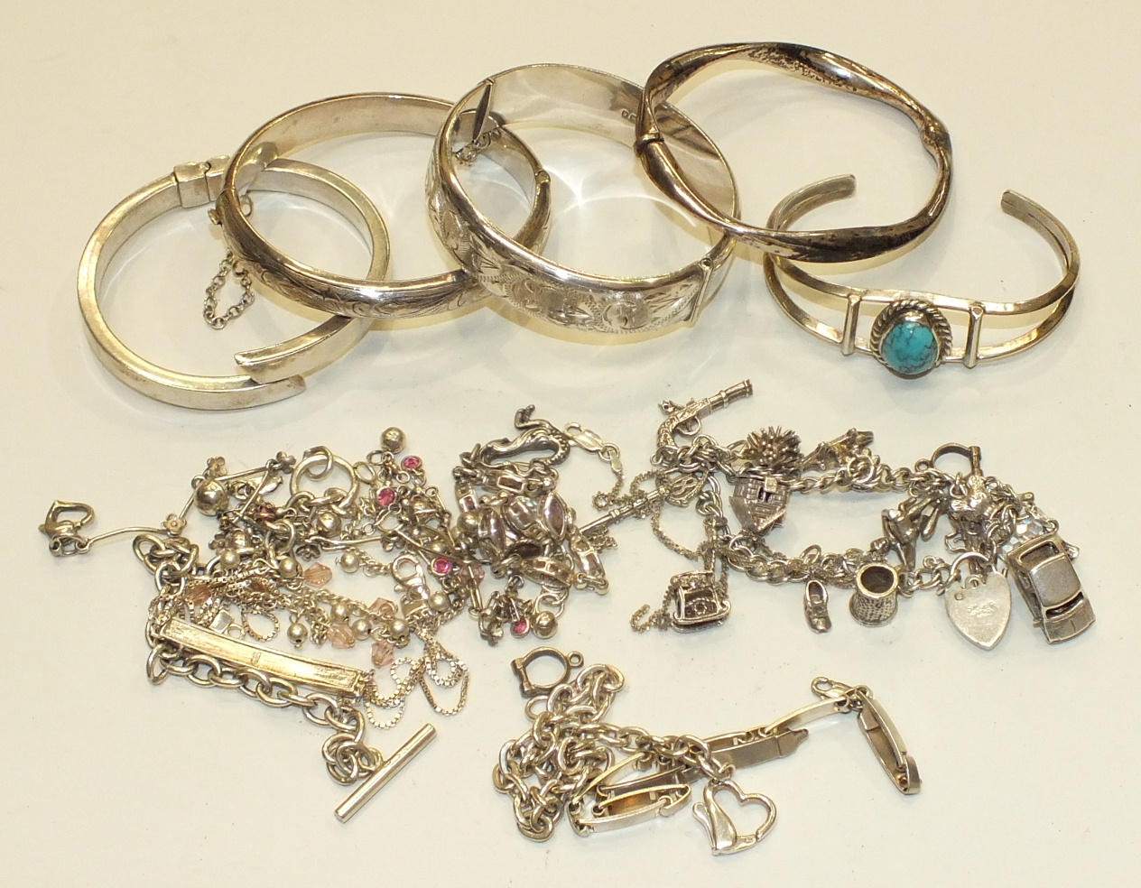 Four silver hinged bangles and other bracelets, charms, etc, 214g.