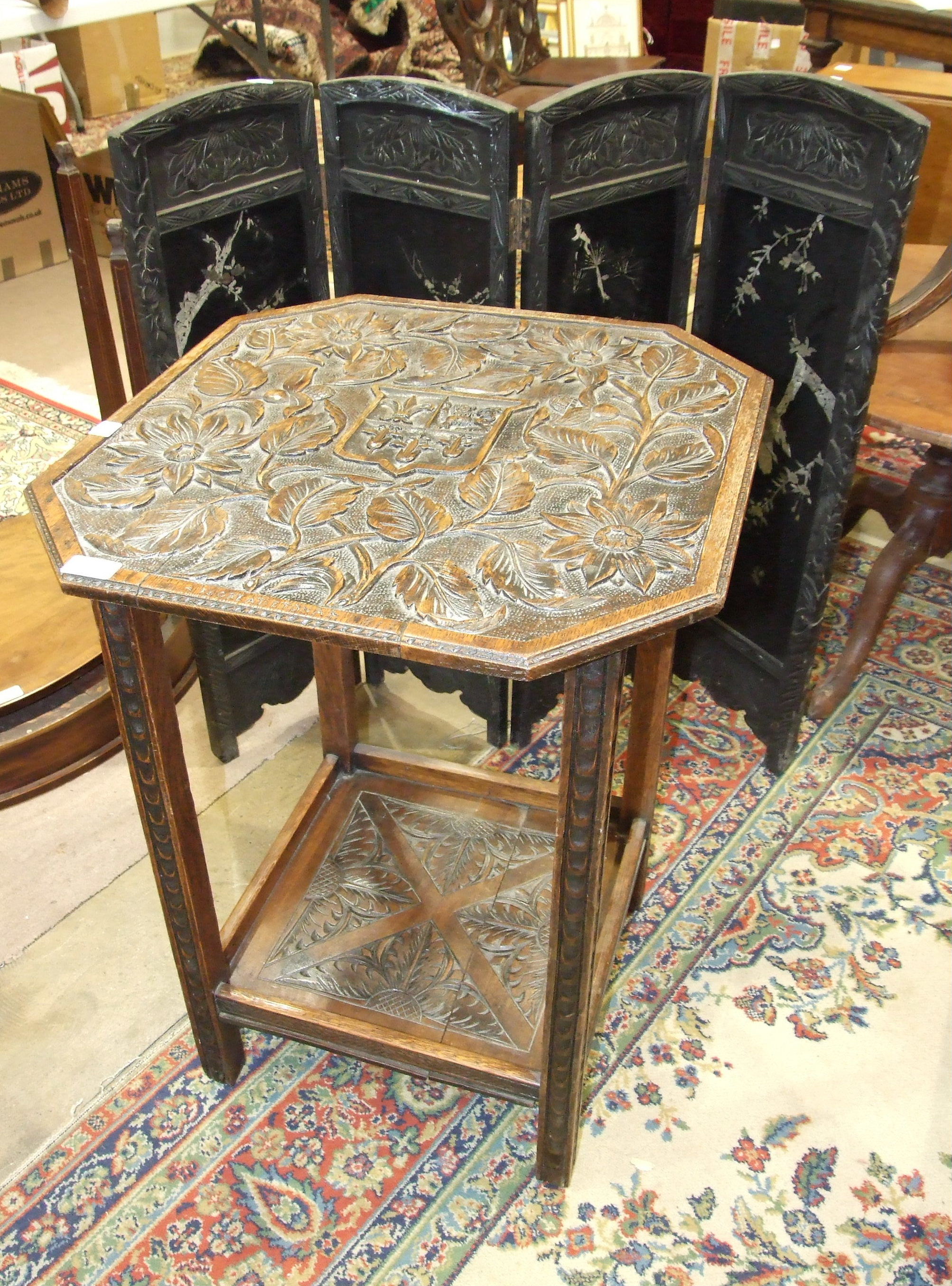 An oak two-tier occasional table carved with flowers and Eton School coat of arms and motto