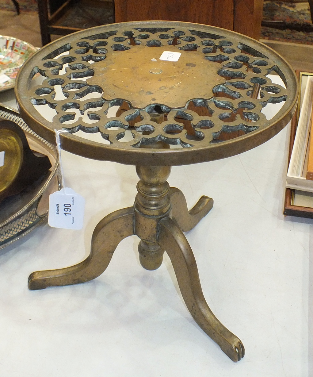 A late-19th century brass trivet with pierced circular top, on triform support.