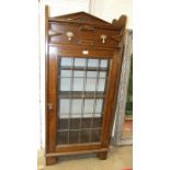 An oak display cabinet, the rectangular top above a single frieze drawer and a pair of leaded-