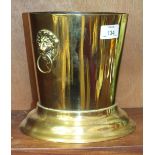 A brass wine cooler of tapering form having applied lion mask and ring handles, 17cm diameter, 19.